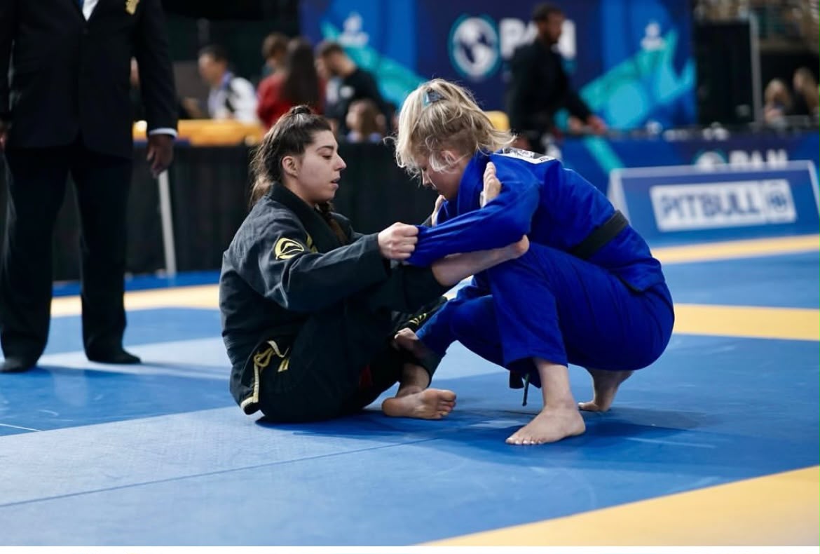 Chayse competing in a BJJ match, working a guard pass against an opponent in blue
